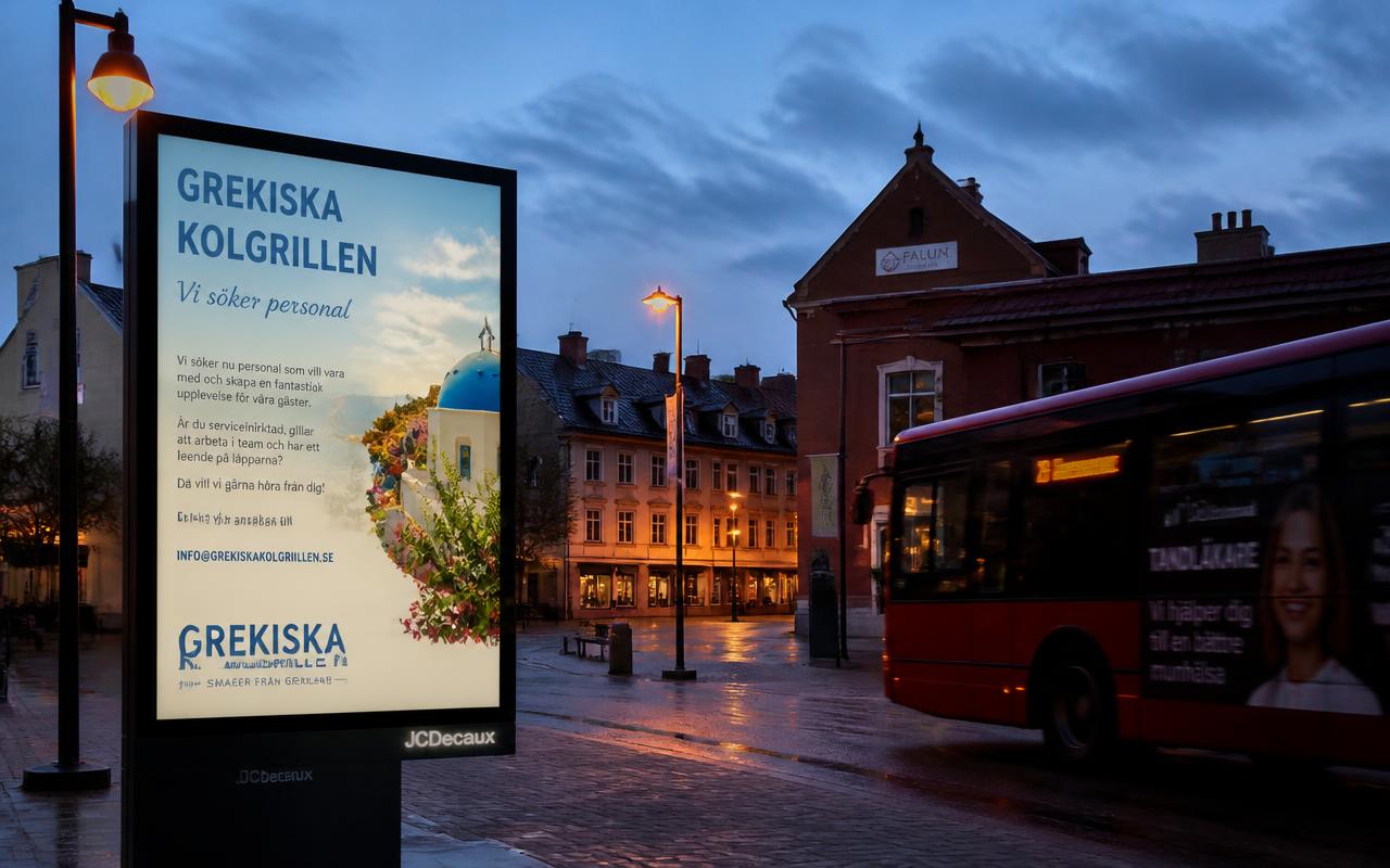 Upplyst reklamskylt på ett torg i en svensk stad i skymningen